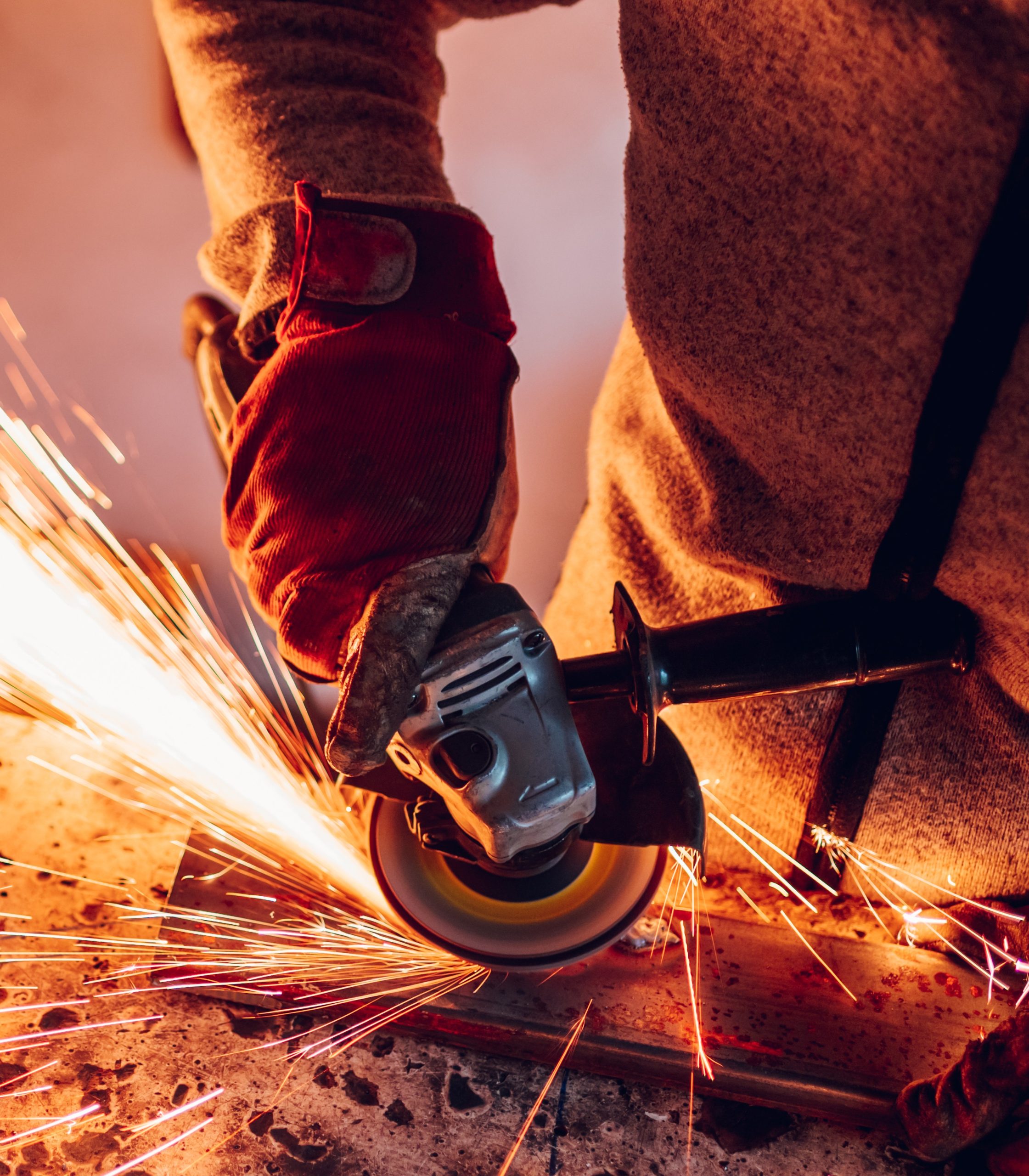 Artigiano taglia il ferro con smerigliatrice angolare e scintille